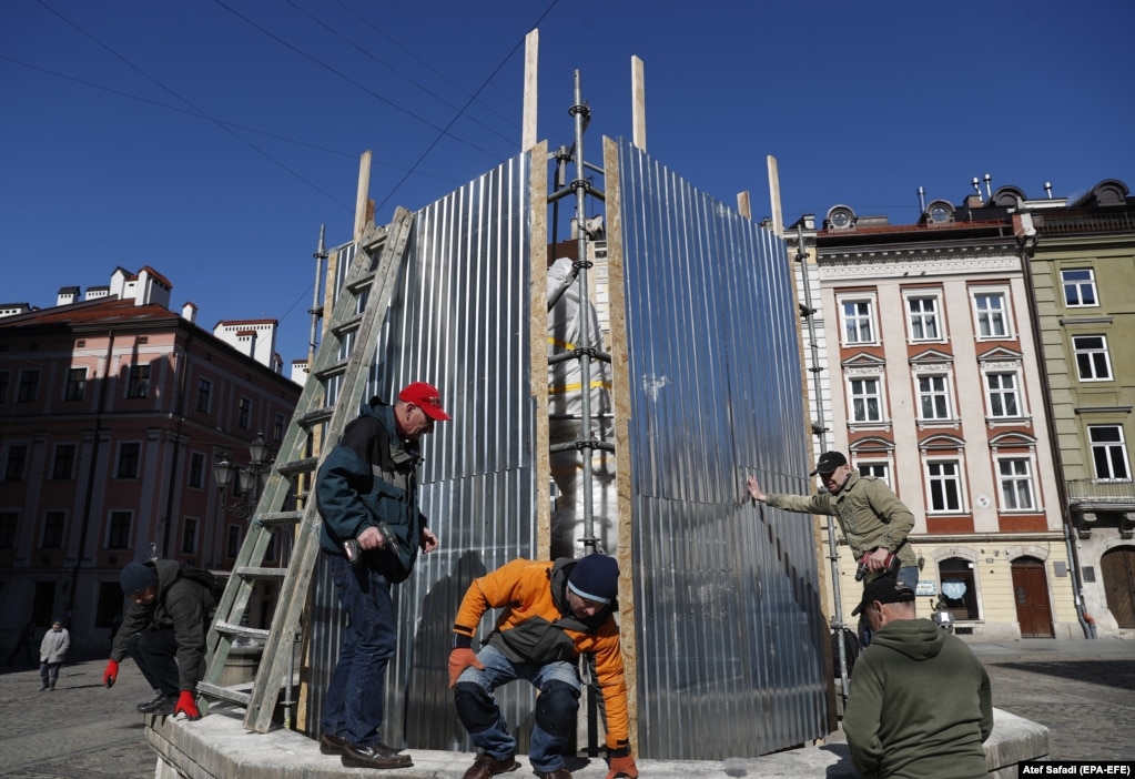 Vullnetarët vendosin një kornizë prej metali përreth një monumenti në Lviv. Barriera të tilla synojnë të mbrojnë monumentet nga valët goditëse, të cilat mund të rrëzojnë statujat pa u goditur drejtpërdrejt nga ndonjë granatë apo edhe nga mbetjet e ndonjë shpërthimi.  
