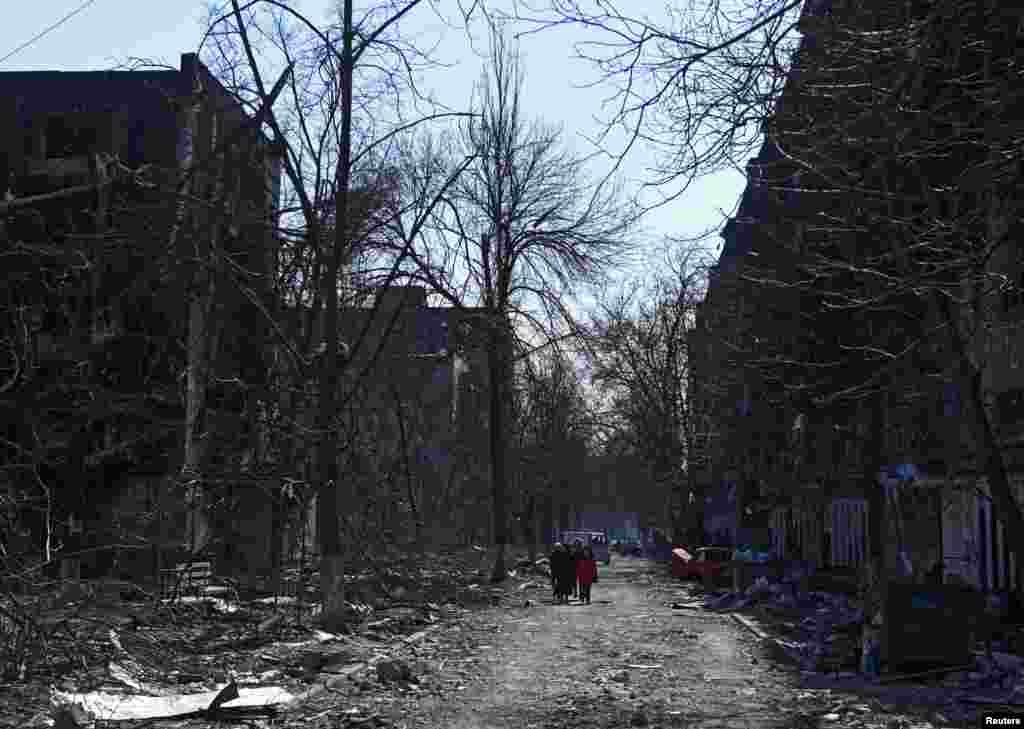 Локалните жители во близина на станбени згради оштетени за време на украинско-рускиот конфликт во опколениот јужен пристанишен град Мариупол, 18 март 2022 година.