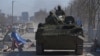 Russia-backed troops in uniforms without insignia drive an armored vehicle in the besieged Ukrainian port city of Mariupol on March 19.