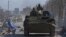 Russia-backed troops in uniforms without insignia drive an armored vehicle in the besieged Ukrainian port city of Mariupol on March 19.