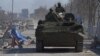 Moscow-backed separatist troops in uniforms without insignia drive an armored vehicle in the besieged southern port city of Mariupol on March 19.