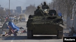 Moscow-backed separatist troops in uniforms without insignia drive an armored vehicle in the besieged southern port city of Mariupol on March 19.