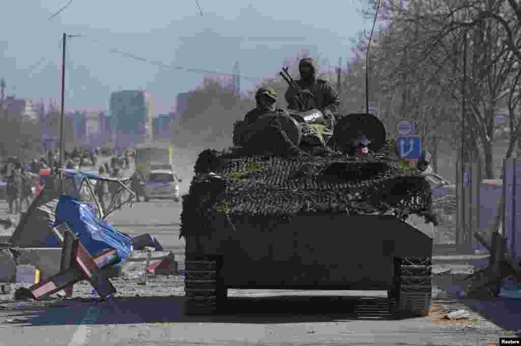 Russia-backed troops in uniforms without insignia drive an armored vehicle in Mariupol on March 19.