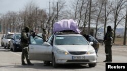 Pripadnici proruskih snaga provjeravaju automobile dok lokalni stanovnici napuštaju opkoljeni južni lučki grad Mariupolj, Ukrajina, 20. marta 2022.
