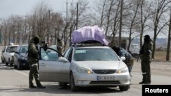 Russian troops check the cars of local residents as they leave the besieged southern port city of Mariupol in Ukraine on March 20. 