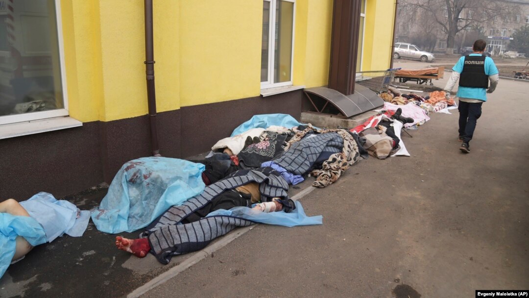A police officer walks past the bodies of people killed by shelling outside Hospital No. 3 in Mariupol.