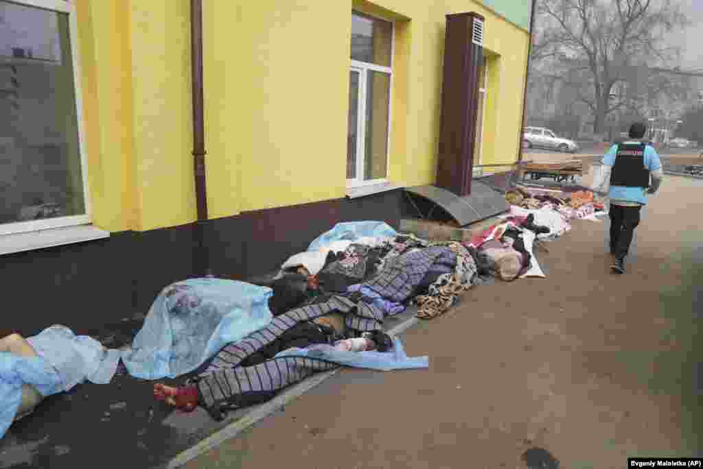 A Ukrainian policeman walks past the bodies of people killed by shelling in Mariupol on March 15.&nbsp;