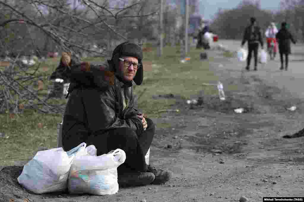 A man sits by the roadside in Mariupol.