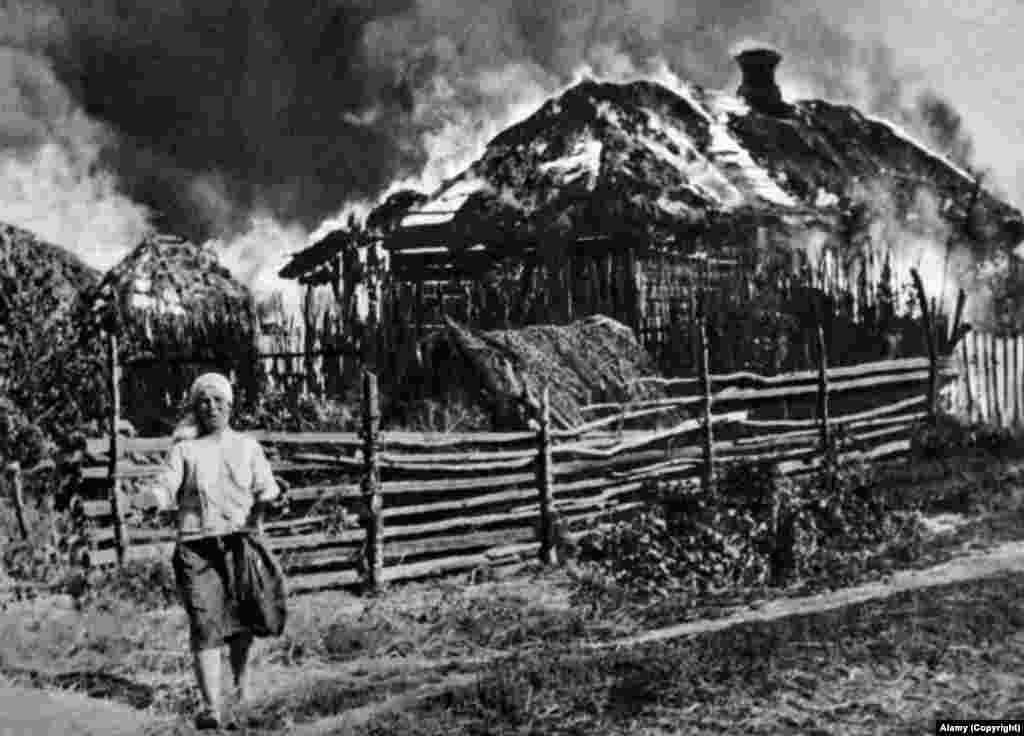 O rusoaică plânge în fața casei sale, care a fost incendiată în timpul ocupației naziste a Uniunii Sovietice (1943).&nbsp; &nbsp;