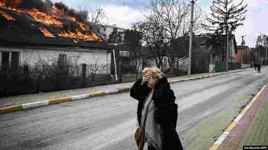 Ukraine -- A woman reacts as she stands in front of a house