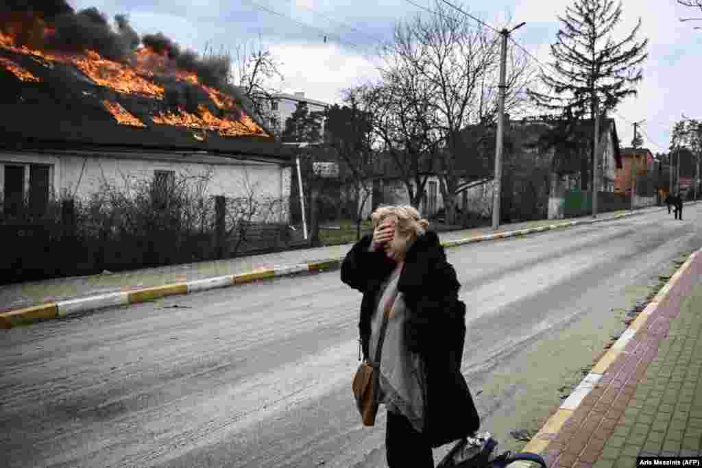 Українка плаче біля свого палаючого будинку, який загорівся внаслідок потрапляння російських снарядів. Ірпінь під Києвом. Україна, 4 березня 2022 року