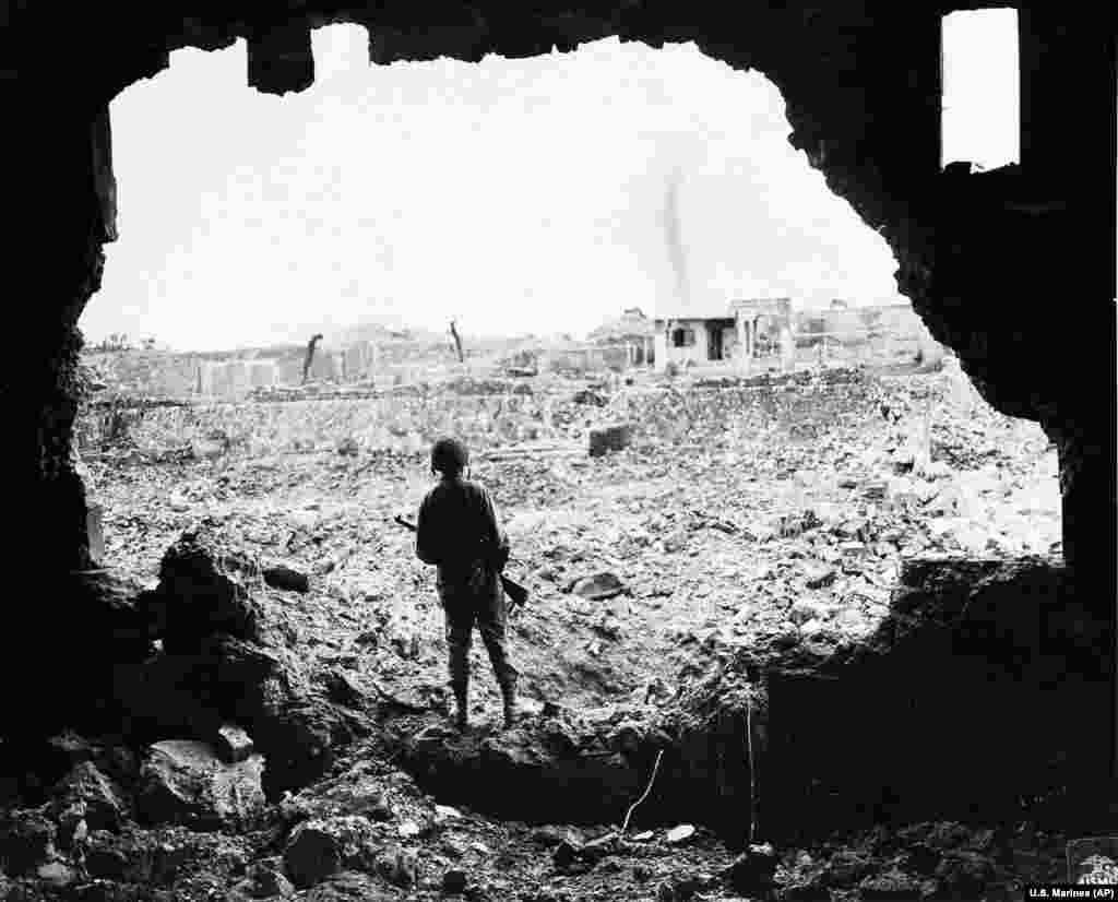 A U.S. Marine surveys the aftermath of the American bombardment of the Japanese town of Naha in the Okinawa prefecture in June 1945.&nbsp;