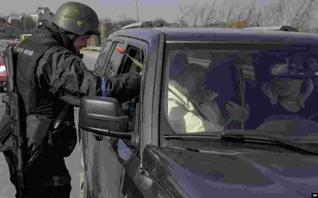 Egy ukrán rendőr tulipánt oszt a női utasoknak és sofőröknek egy ellenőrző ponton Kijev külvárosában március 20-án