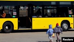 Két menekült ukrán gyerek fut egy busz felé az újonnan épített érkezési központban az egykori Tegel repülőtér területén. Berlin, Németország, 2022. március 22.