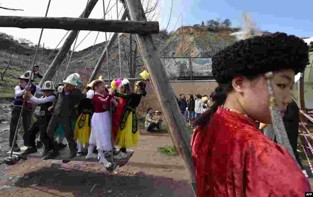 Children wearing traditional costumes play on a swing during Norouz celebrations in Bishkek.