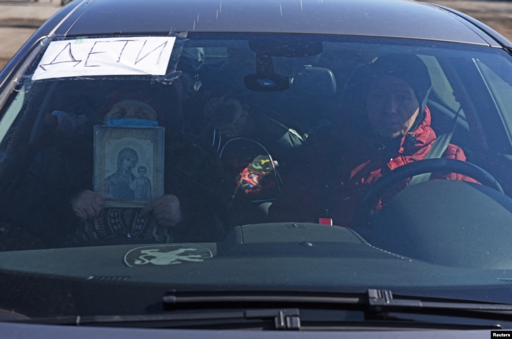 Маріупольці намагаються виїхати з міста на автомобілі, один із пасажирів тримає  ікону. На табличці у вікні написано: «Діти». Маріуполь, 19 березня 2022 року