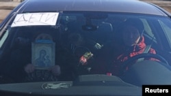 Мариупольцы пытаются выехать из города на автомобиле, один из пассажиров держит икону. Мариуполь, 19 марта 2022 года
