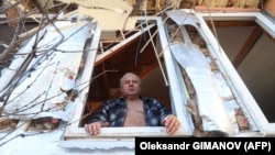 Последствия одного из предыдущих обстрелов Одессы российскими войсками: пожилой мужчина смотрит из окна своего разрушенного дома