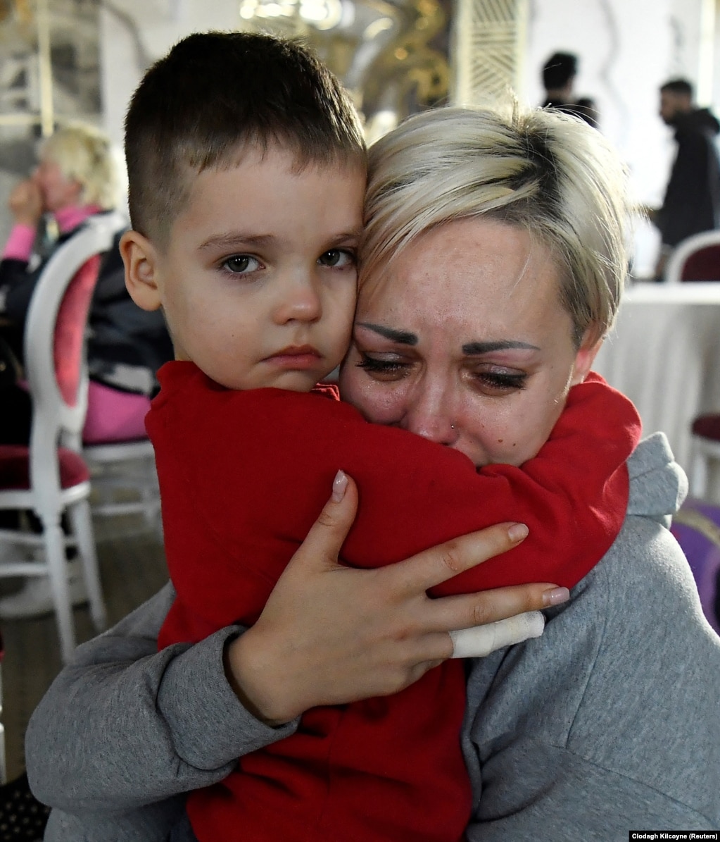 Українка зі своїм сином плаче у бальному залі, переобладнаному на тимчасовий притулок. Сучава, Румунія, 20 березня 2022 року. Чоловік жінки та син-підліток залишилися в Україні