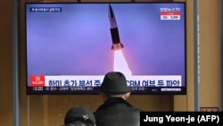 Ljudi prate televizijski program vesti i arhivsku fotografiju lansiranja rakete Severne Koreje, na železničkoj stanici u Seulu, 16. marta 2022.