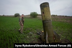 Украинский солдат рядом с хвостовой частью ракеты «Точка У» в Харьковской области, апрель 2022 года
