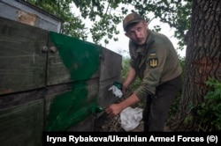 A Ukrainian soldier paints over the 'Z' of a captured Russian armored vehicle.