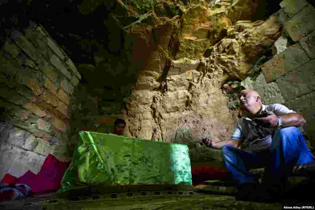 Qobustan rrayonunda Diri Baba türbəsi. Dua edən ziyarətçi və Quran oxuyan cavan oğlan.