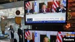 Women walk outside an electronics shop in the West Bank city of Ramallah during a TV broadcast showing Binyamin Netanyahu, U.S. Secretary of State Hillary Clinton, and Mahmud Abbas on September 2.