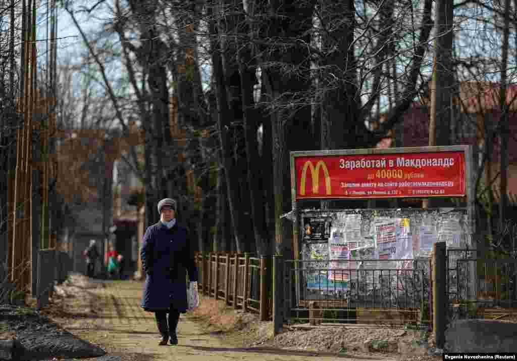 A woman walks along a street past an old banner offering jobs at McDonald&#39;s in the town of Pokrov in the Vladimir region, outside Moscow.&nbsp;McDonald&#39;s -- like Starbucks and IKEA -- announced on March 14 that it is closing all its stores inside Russia in response to the invasion of Ukraine.