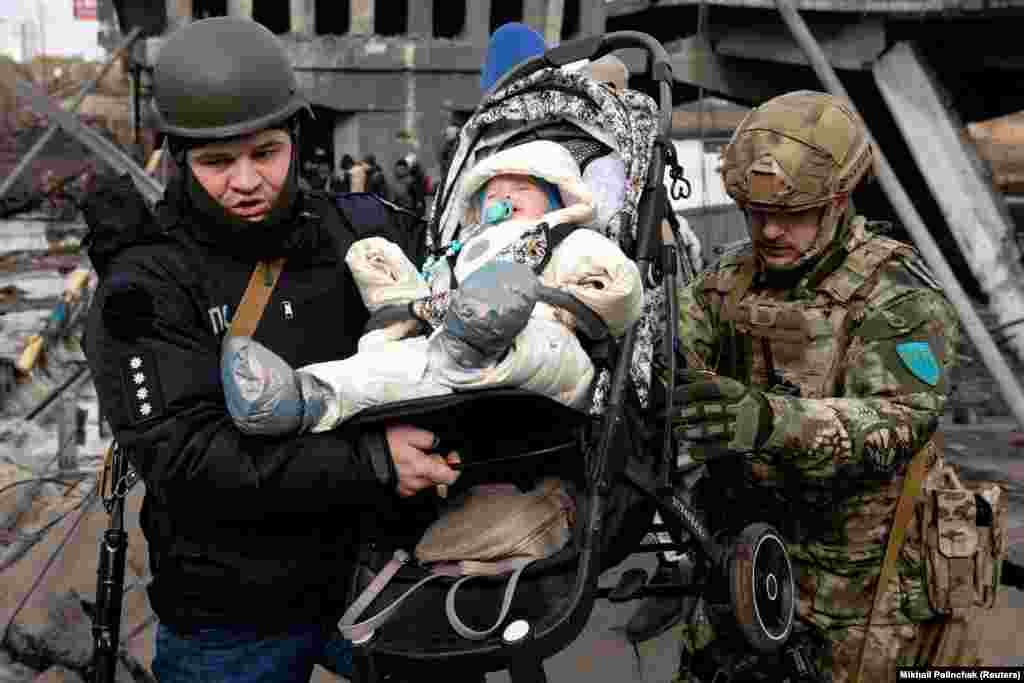 Katonák segítenek át a lebombázott irpinyi hídon egy kisbabát március 9-én, a város evakuálása közben