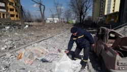 Un salvator acoperă cadavrul unei persoane ucise în urma bombardamentelor în zona rezidențială a Cernigăului. Imagine din 17 martie 2022.