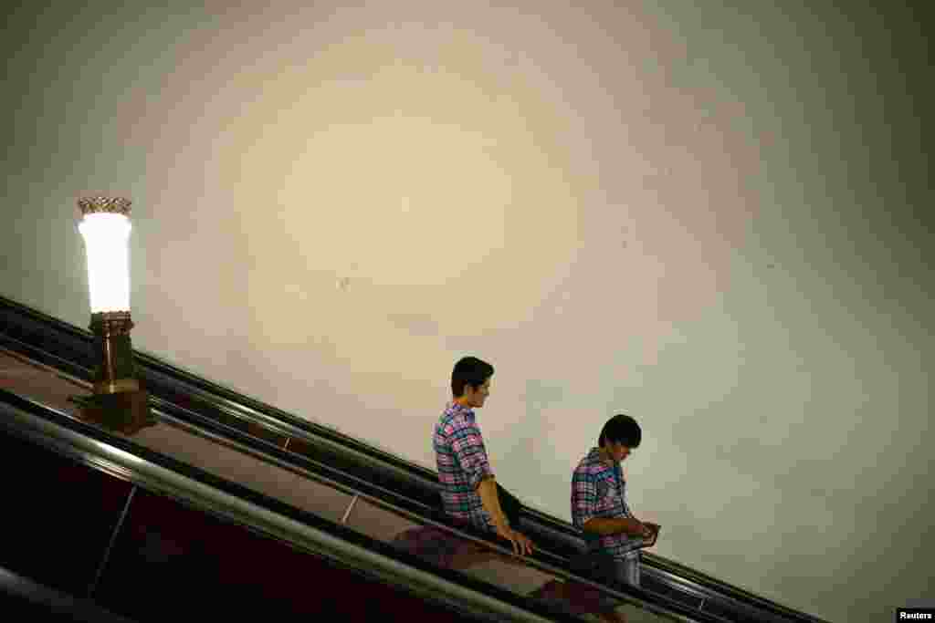 Two men go down an escalator at a Moscow metro station.