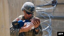Американски морски пехотинец с бебе в ръце на летището в Кабул. Снимката е разпространена от американската армия.