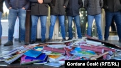 Okupljeni studenti bacili su stare udžbenike ispred Ministarstva prosvete. Iza udžbenika, na ulazu u Ministarstvo, stajali su pripadnici policije u civilu i obezbeđenja zgrade. U Beogradu 27. decembra 2024.