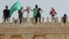 Palestinac drži zastavu Hamasa dok stoji pored drugih na vrhu džamije Al-Aksa nakon sukoba s izraelskom policijom u kompleksu u kojem se nalazi džamija, poznatom muslimanima kao Plemenito utočište, a Jevrejima kao Brdo hrama, Stari grad Jerusalim, maj 2021.