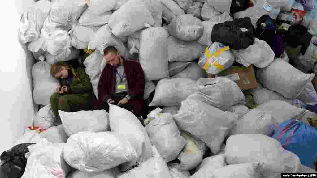 UKRAINE - Volunteers rest amongst bags of clothes that needed to be sorted and distributed in Lviv, March 19.