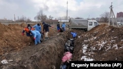 Тіла загиблих цивільних кладуть у братську могилу на околиці Маріуполя, оскільки люди не можуть поховати своїх загиблих через сильний обстріл з боку російських військ. Маріуполь, 9 березня 2022 року