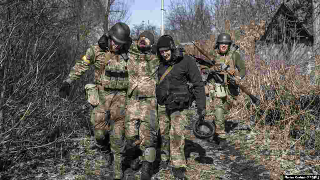 Побратими допомагають пораненому українському бійцю після бою з російськими військами в Київській області 10 березня 2022 року