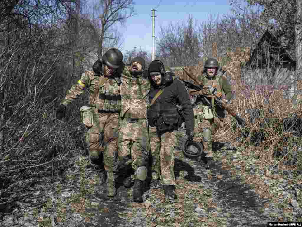 Побратими допомагають пораненому українському бійцю після бою з російськими військами в Київській області 10 березня 2022 року