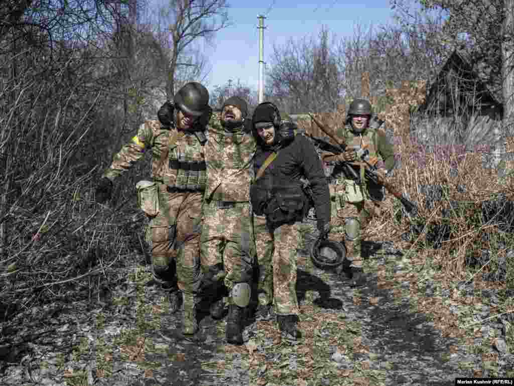 Un soldat ucrainean rănit, ajutat să ajungă într-un loc sigur, în urma unui schimb de focuri de armă din regiunea Kiev (10 martie).&nbsp;