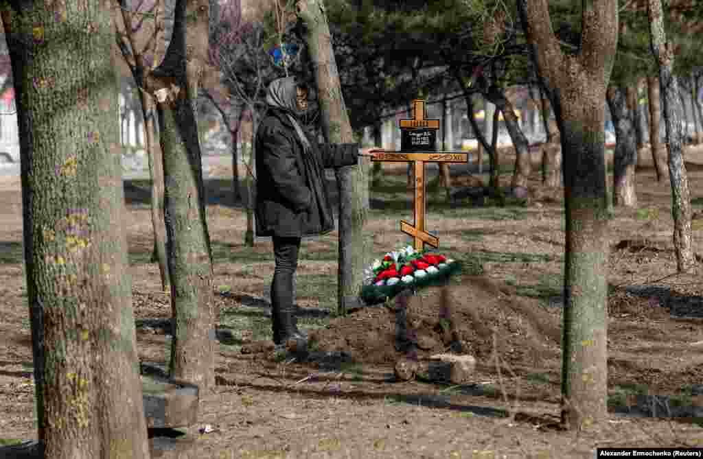 A woman stands next to the grave of her mother, a week after she was killed by shelling in Mariupol.&nbsp;