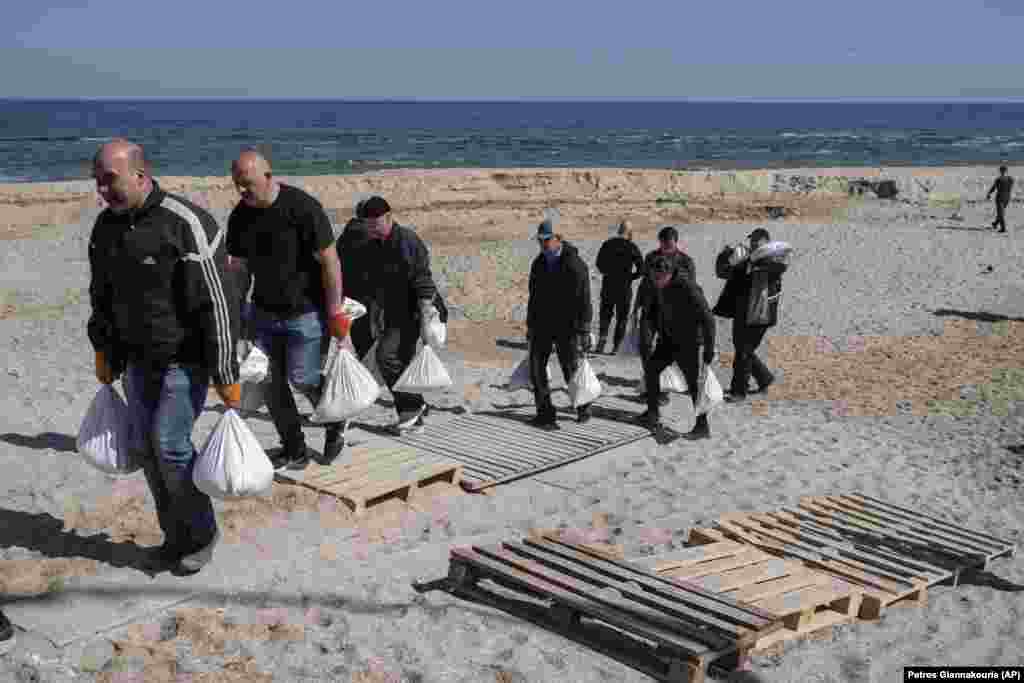 Volunteers carry sandbags used to barricade sites inside Odesa on March 23. The southern city has so far been largely untouched by the invasion, but Russian ships have been spotted off the coast.&nbsp;