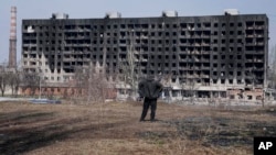 A man looks at a burned apartment building that was damaged by shelling in Mariupol on March 13. 