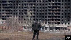 Маж гледа гранатирана зграда во Мариупол, март 2022