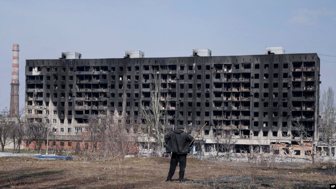 Un bărbat se uită la un bloc de apartamente incendiat care a fost avariat de bombardamente în Mariupol pe 13 martie. Foto: AP
