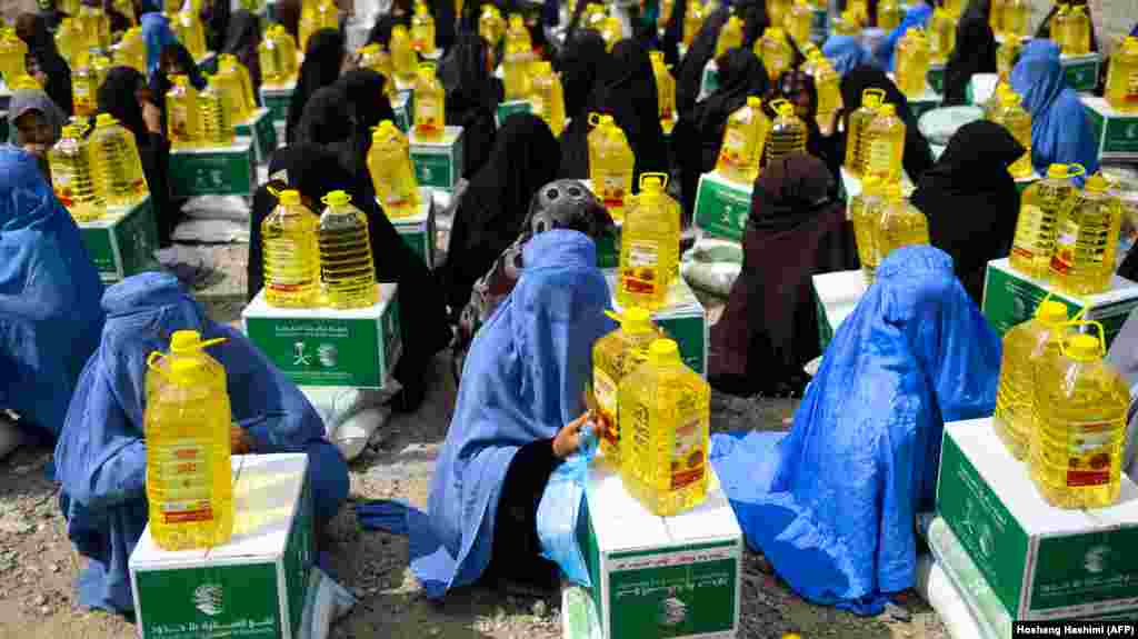 Afghan burqa-clad women sit as they receive aid items by a charity during the holy month of Ramdan in Herat Province on May 23. (AFP/Hoshang Hashimi)&nbsp;