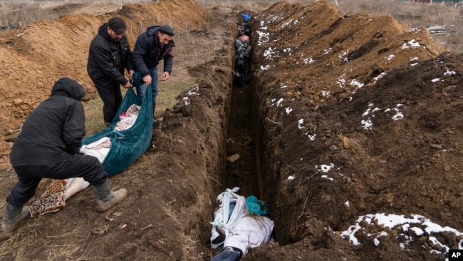 Тела погибших кладут в братскую могилу на окраине Мариуполя. Март 2022 г.