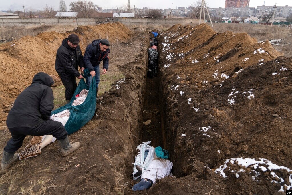 Dead bodies are placed into a mass grave on the outskirts of Mariupol on March 9.