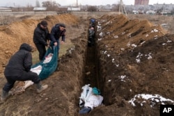 Dead bodies are placed into a mass grave on the outskirts of Mariupol on March 9.