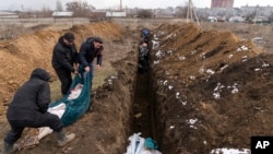 Cadavrele sunt puse într-o groapă comună de la periferia orașului Mariupol pe 9 martie.